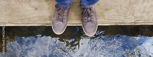Banner with legs in brown moccasins on background mountain river. Feet of woman or man in brown shoes standing on wooden log above water. Concept of life balance, lifestyle. Header for website, blog photo