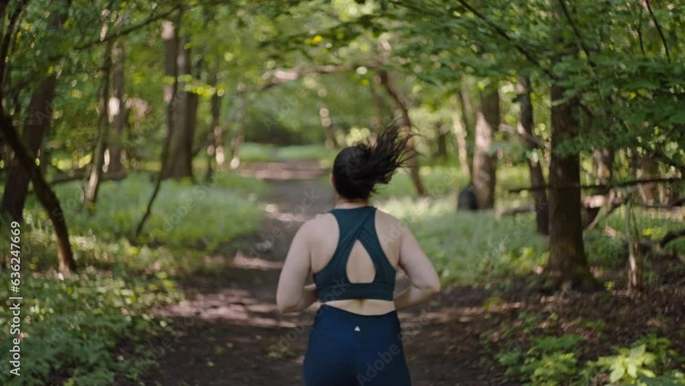 Beautiful overweight plus size girl is running on a path in the forest. Exercise and fitness for weight loss. A woman with an active lifestyle. High quality 4k footage Beautiful overweight plus size girl is running on a path in the forest. Exercise and fitness for weight loss. A woman with an active lifestyle. High quality 4k footage
