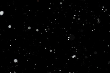 Bokeh effect of snowfall and lights. Abstract blurred background with snowflake in the night sky, White spots and dots in the dark. Snowy stormy weather, falling snow