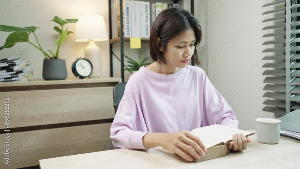 Asian women reading a book while sitting on the chair in the living room. relaxing and lifestyle concepts ,Wellness at home. Asian women reading a book while sitting on the chair in the living room. relaxing and lifestyle concepts ,Wellness at home.