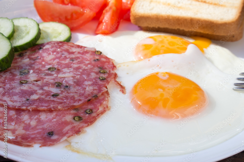 A close-up photograph of a breakfast, featuring fried eggs, salami, croutons. A close-up photograph of a breakfast, featuring fried eggs, salami, croutons.