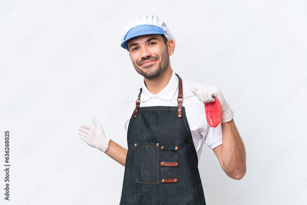 Butcher caucasian man wearing an apron and serving fresh cut meat over isolated white background extending hands to the side for inviting to come Butcher caucasian man wearing an apron and serving fresh cut meat over isolated white background extending hands to the side for inviting to come