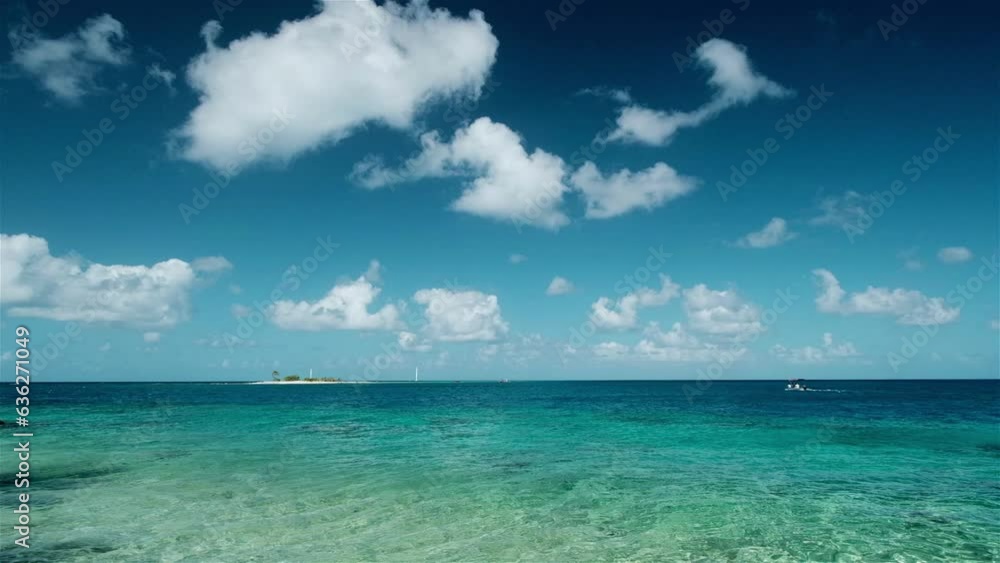Blue skies and turquoise waters with a small island and boat on a perfect day in the tropical islands of Tuamoto Atolls in the South Pacific Blue skies and turquoise waters with a small island and boat on a perfect day in the tropical islands of Tuamoto Atolls in the South Pacific