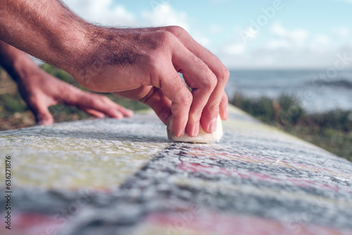 Photography Crop man covering surfboard with wax on seaside
