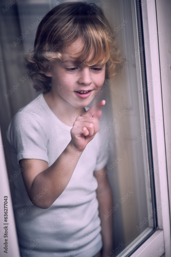 Happy little child drawing on misted window glass Happy little child drawing on misted window glass