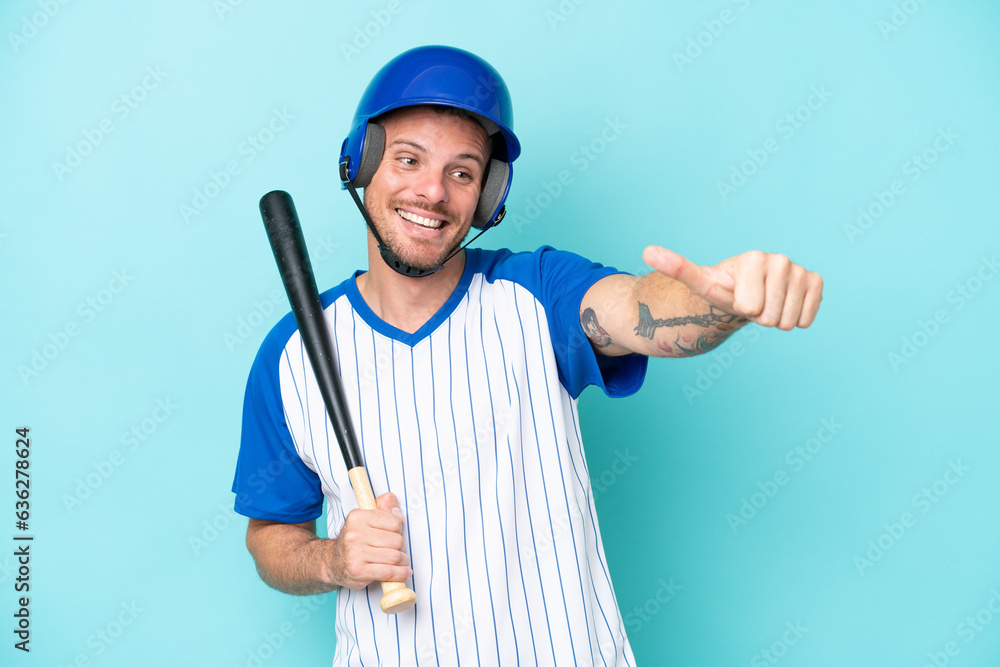 Baseball player with helmet and bat isolated on blue background giving a thumbs up gesture Baseball player with helmet and bat isolated on blue background giving a thumbs up gesture