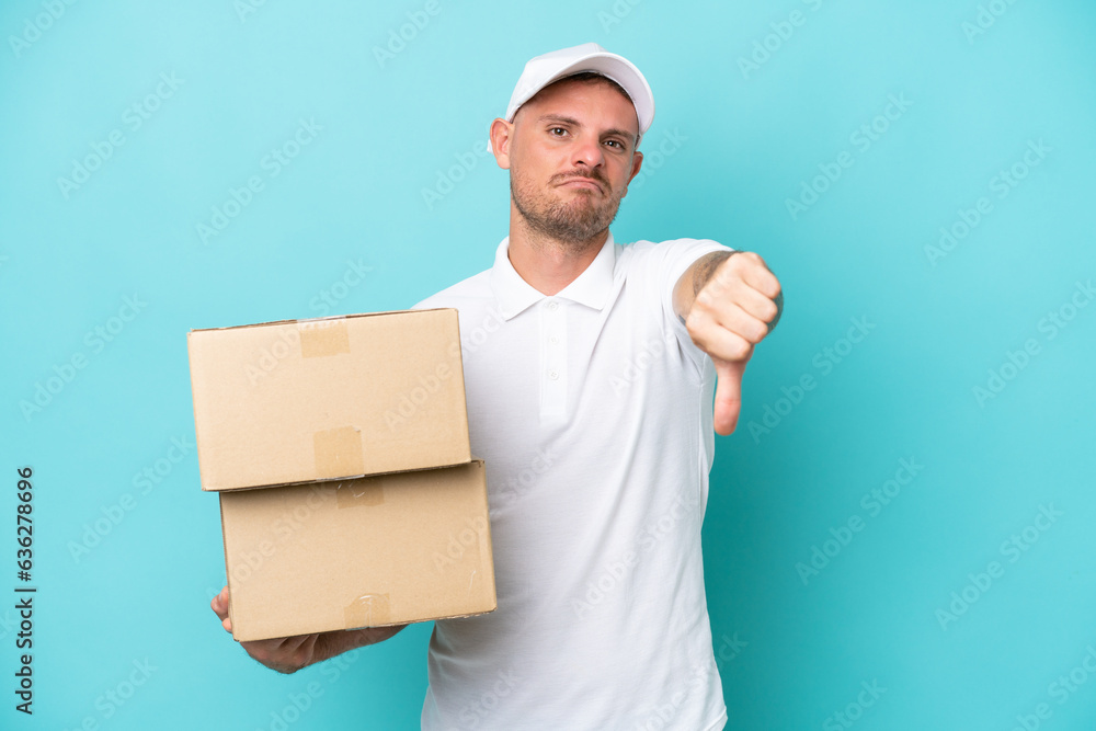 Delivery caucasian man isolated on blue background showing thumb down with negative expression Delivery caucasian man isolated on blue background showing thumb down with negative expression