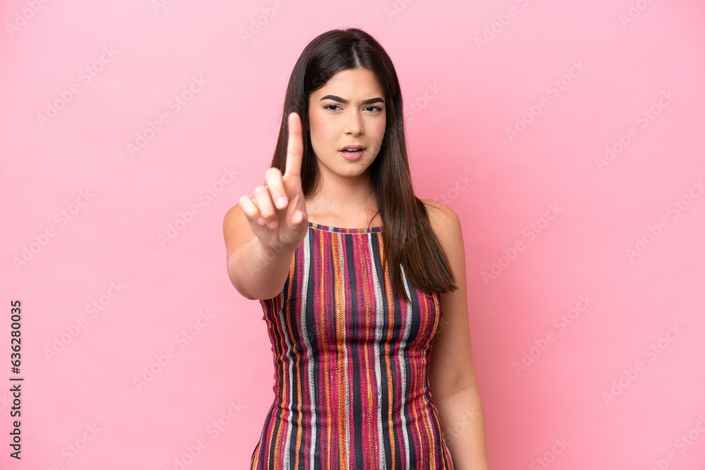 Young Brazilian woman isolated on pink background counting one with serious expression Young Brazilian woman isolated on pink background counting one with serious expression