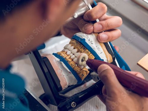 Crop prosthetist man polishing implants of artificial teeth of j photo