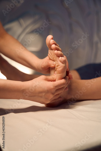 Experienced masseuse massaging client foot with hands © Svitlana