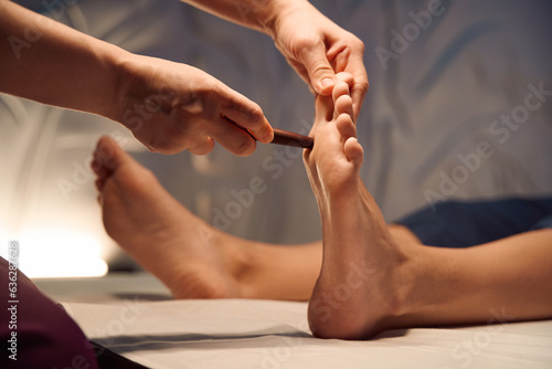 Experienced masseuse giving woman Thai foot massage