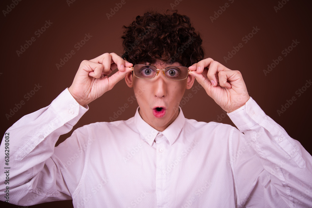 Funny young guy posing in the studio on a brown background. Funny young guy posing in the studio on a brown background.