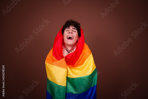 Young attractive guy posing with a gay flag. © vladorlov