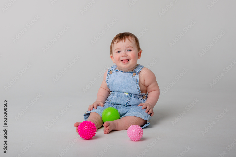baby boy sitting on a white background playing with colored balls baby boy sitting on a white background playing with colored balls