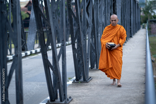 Buddhist monks are morning walking on routes between rural villages on the ancient iron bridge the travel destination of Chiang Mai, Thailand.