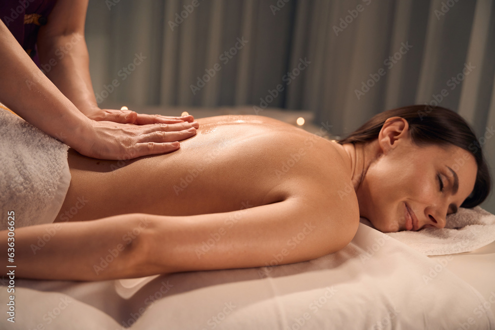 Fototapeta premium Masseuse warming up client lumbar muscles during massage session