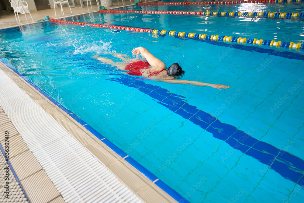 Athletic woman swimming front crawl in pool
