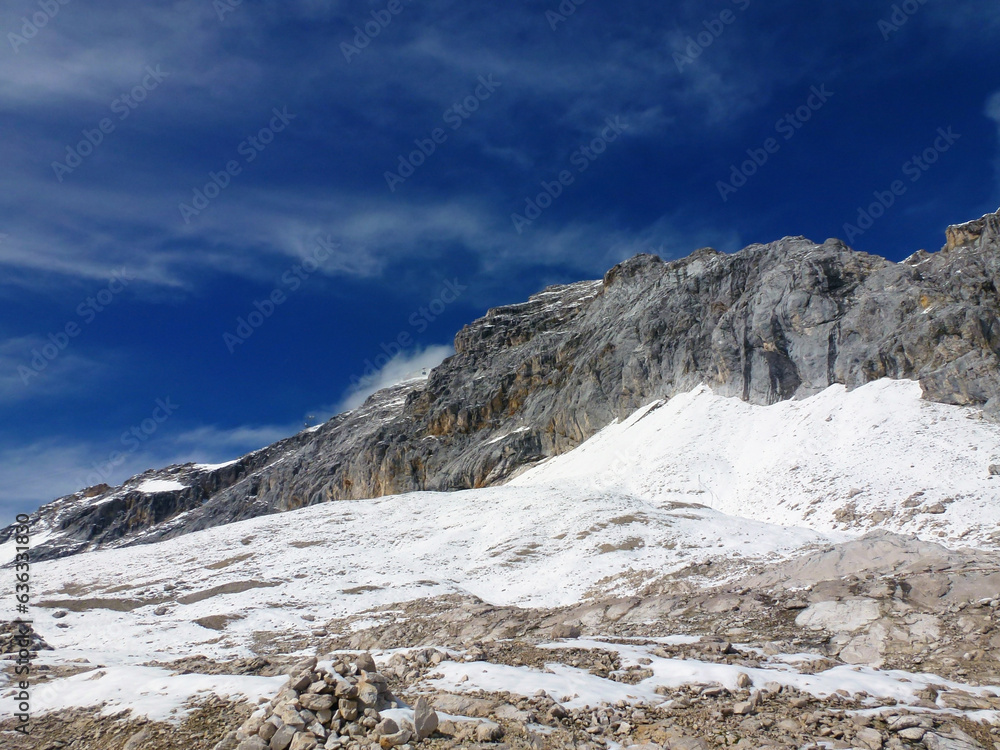 Rocky mountain snow-capped peaks on the background of a bright blue sky.