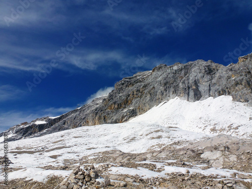 Rocky mountain snow-capped peaks on the background of a bright blue sky.