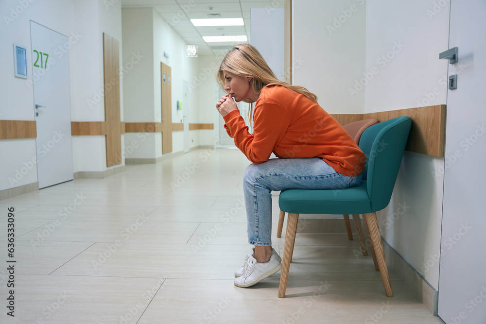 Frustrated woman sits in a hospital corridor Frustrated woman sits in a hospital corridor