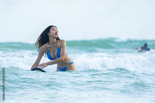 Asian female surfer in swimsuit holding a surfboard
