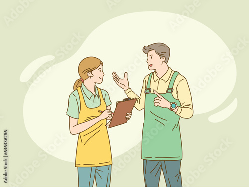 Woman in apron with clipboard speaks with man in apron.