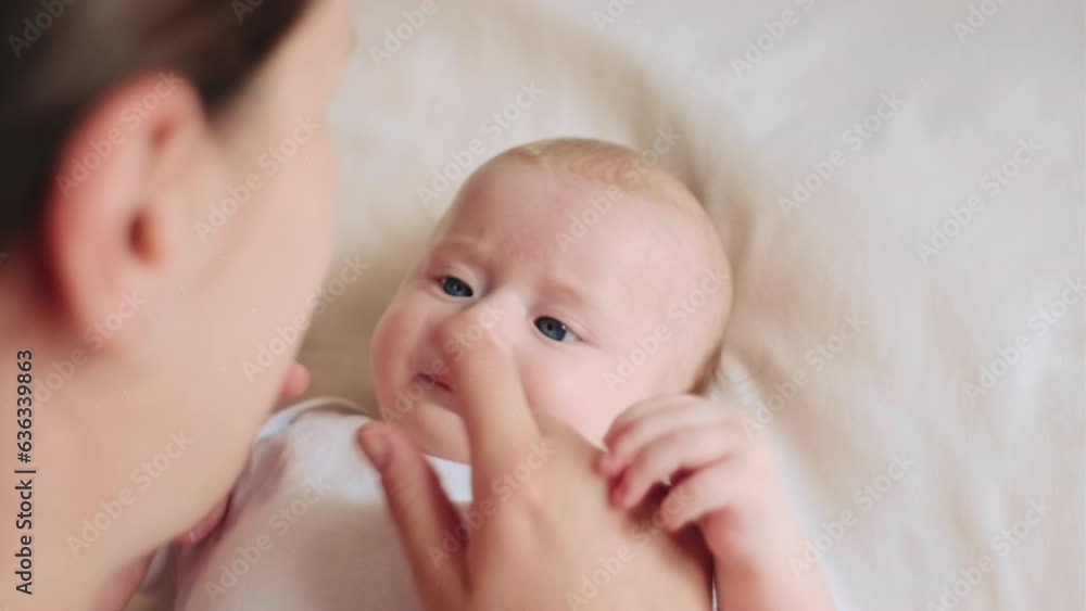 Side view of loving young mom with infant baby lying on cozy bed at home, cuddling, adorable child, enjoying childcare, motherhood, parenting, caressing kid with affection, tenderness concept Side view of loving young mom with infant baby lying on cozy bed at home, cuddling, adorable child, enjoying childcare, motherhood, parenting, caressing kid with affection, tenderness concept
