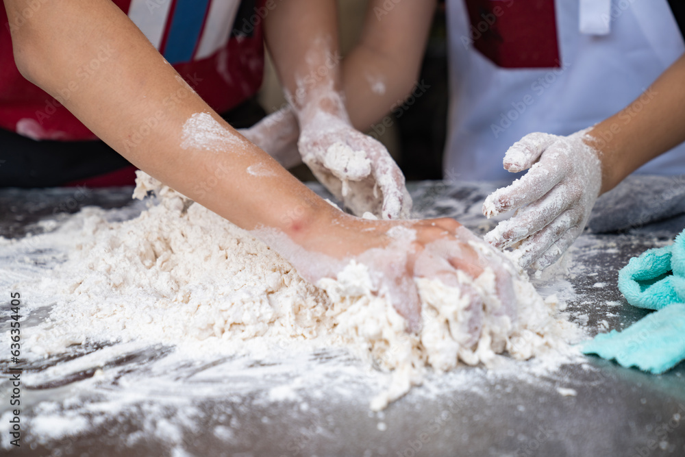 Two skilled Asian men showcase their expertise as they deftly work together, their four hands skillfully kneading and threshing flour on aluminum plate, in preparation for crafting fresh Two skilled Asian men showcase their expertise as they deftly work together, their four hands skillfully kneading and threshing flour on aluminum plate, in preparation for crafting fresh