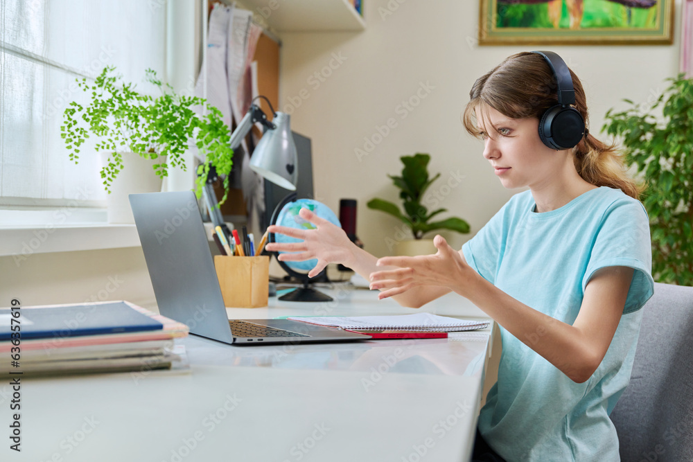 Preteen girl in headphones having video lesson on laptop, at home Preteen girl in headphones having video lesson on laptop, at home