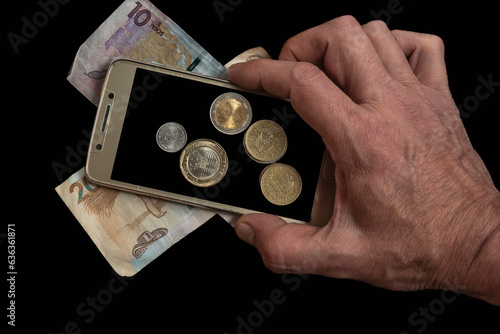 Businessman holding Colombian coins on the background of a cell phone screen