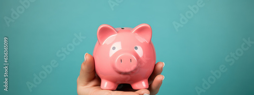 Women's hands in a red and blue casual jumper holds a pink piggy bank on a blue background. Created with Generative AI technology.