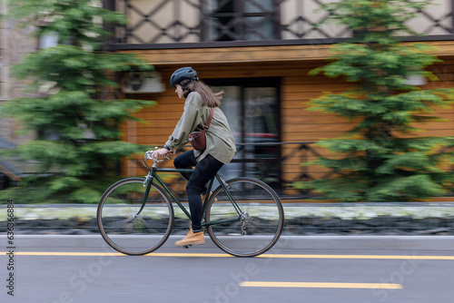 Woman rides bicycle fast in the street with blurred in motion background