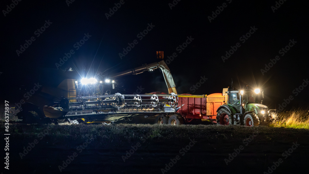 Combine harvester working at night. Offloading rain to a tractor trailer. Combine harvester working at night. Offloading rain to a tractor trailer.