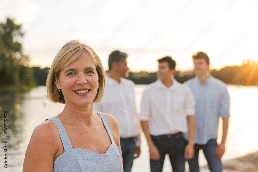 outdoor portrait of caucasian proud woman and mother with her family in background