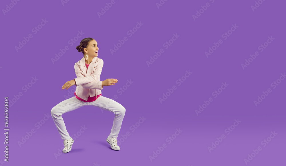Full body length shot of happy funny cheerful pretty little girl in light pink leather jacket and white jeans dancing on purple copy space background. Children's clothes, kid's fashion, sale concept