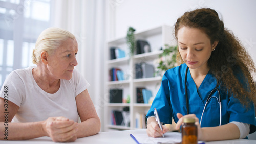 Young woman physician prescribing dietary supplements to senior woman at home