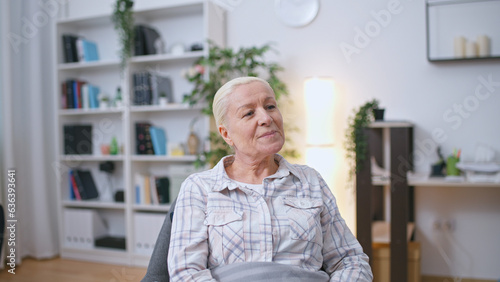 Smiling woman with gray hair sitting on chair in a living room of a nursing home