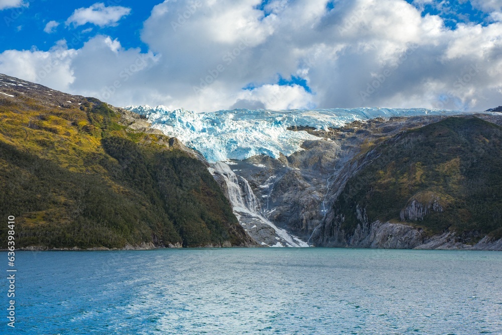 Waterfall cascading down from a mountain range into the tranquil Beagle Channel in Chilean Fjords