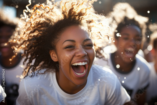 A group of African American teens their faces beaming with joy run together laughing and splashing through a fountain.
