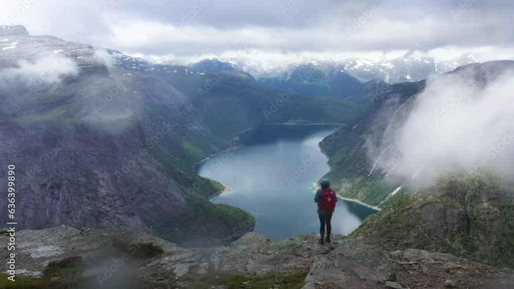 Female Hiker in Norway overlooking the Mountains and Fjord on a cloudy day Female Hiker in Norway overlooking the Mountains and Fjord on a cloudy day
