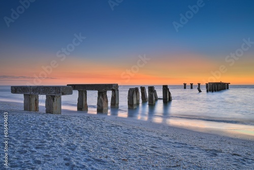 Old broken pier on the Florida island of Boca Grande just after sunset. © Greg Kullman/Wirestock Creators