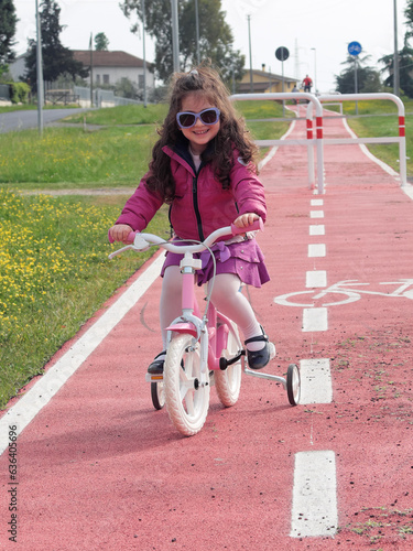 Bambina in bicicletta sulla pista ciclabile photo