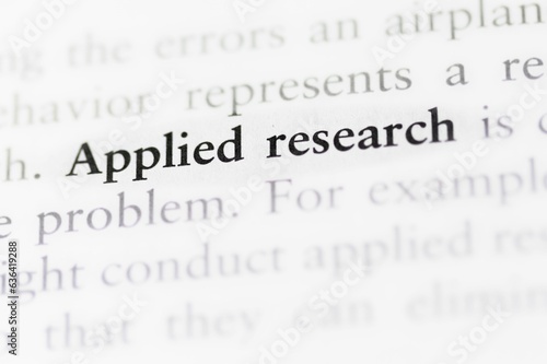 Close-up of a textbook with the term 'applied research' highlighted and focused