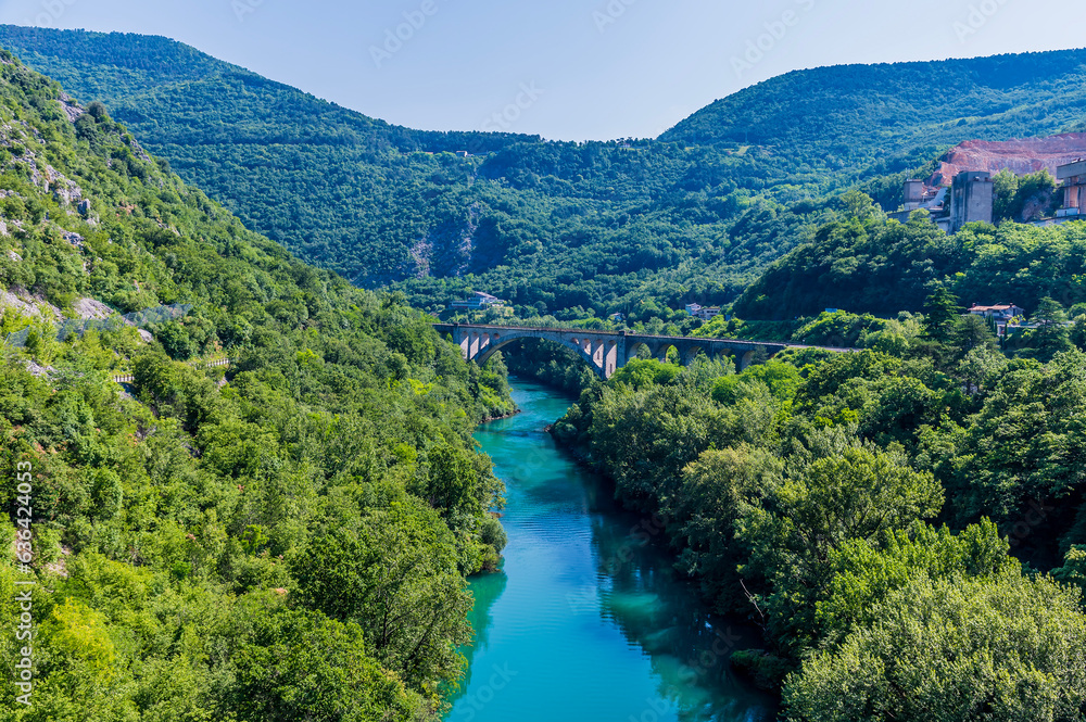 A view down the Soca river towards the largest stone arch railway bridge at Solkan in Slovenia in summertime