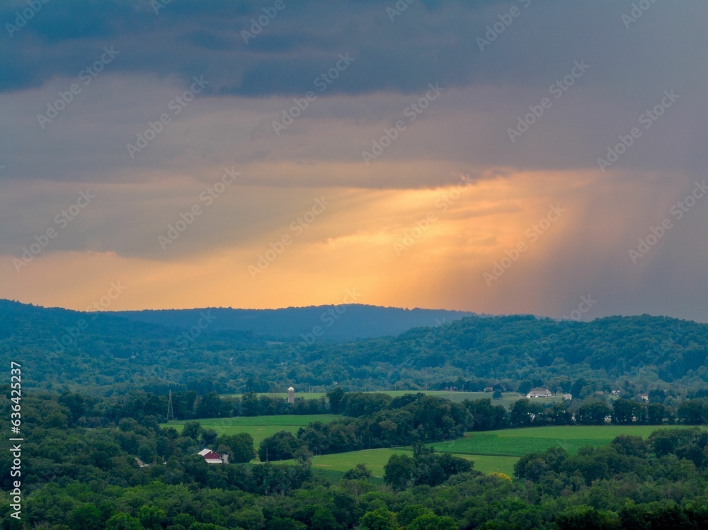 Obraz premium Aerial view of an idyllic rural farm with a spectacular sunset sky in the background