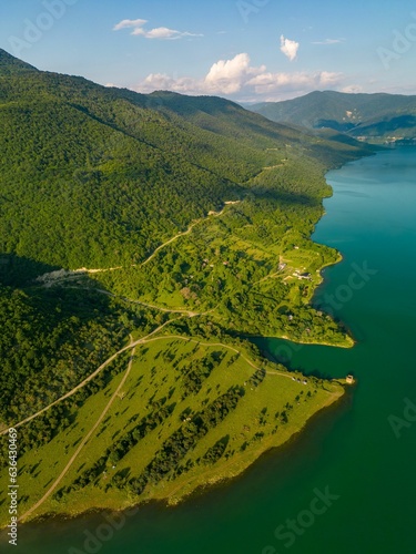 Aerial view of a lake surrounded by green mountains on a sunny day