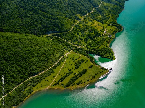 Photography Aerial view of a lake surrounded by green mountains on a sunny day