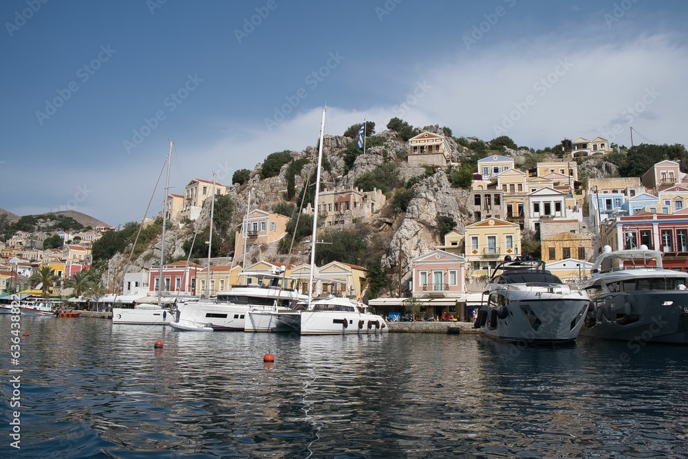 Picturesque view of a tranquil town nestled on the shore of the sea in Symi island, Greece.