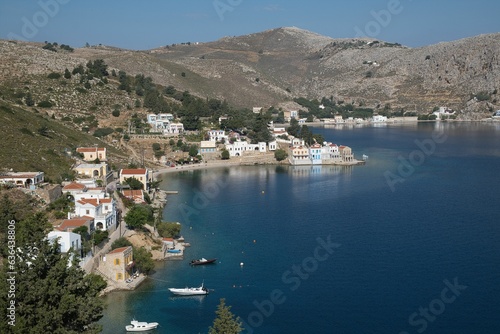 Picturesque view of a tranquil town nestled on the shore of the sea in Symi island, Greece.