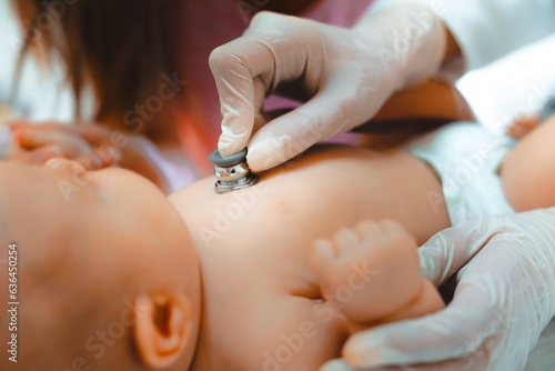 Close up of doctor examining baby with stethoscope in hospital - Stock Photo photo